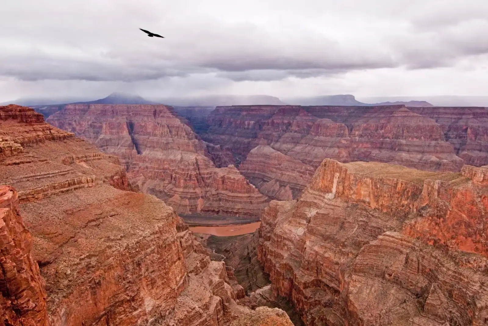 Scenic view of the Grand Canyon with layered red rock formations and the Colorado River running through the valley.