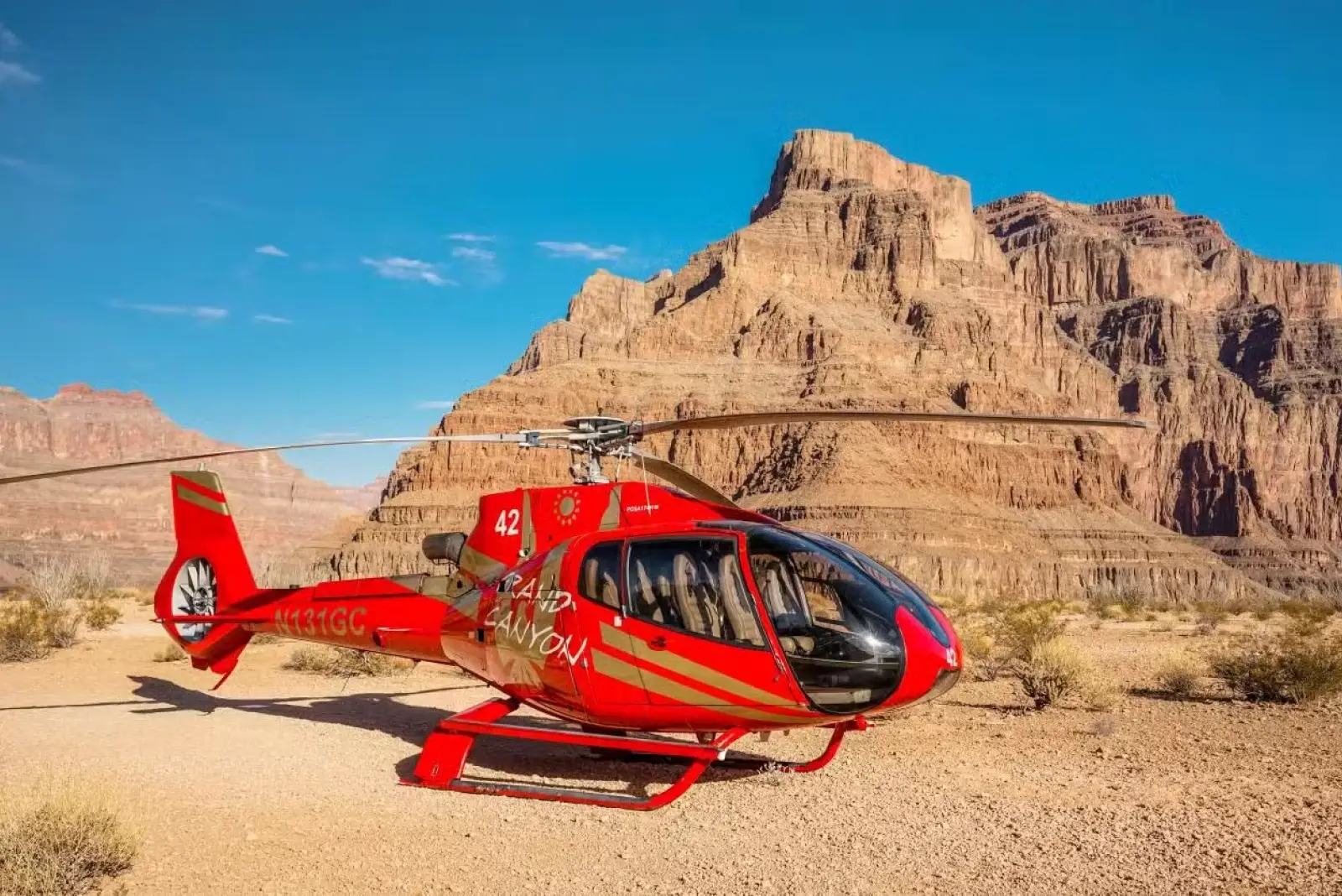 Scenic view of the Grand Canyon with layered red rock formations and the Colorado River running through the valley.